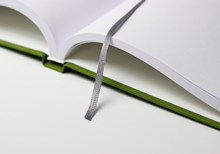Hardcoverbuch in grünem Leinen, aufgeschlagen, mit Leseband